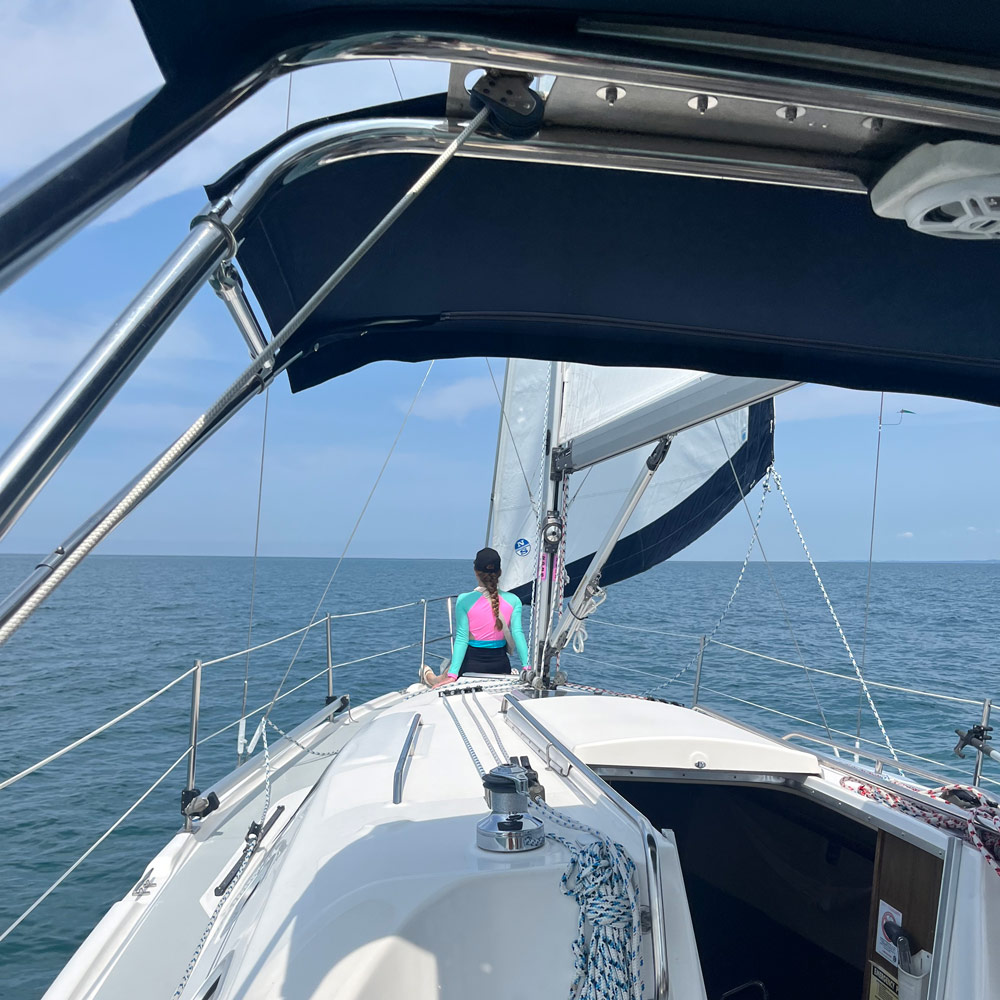 persom sitting at front of sailboat